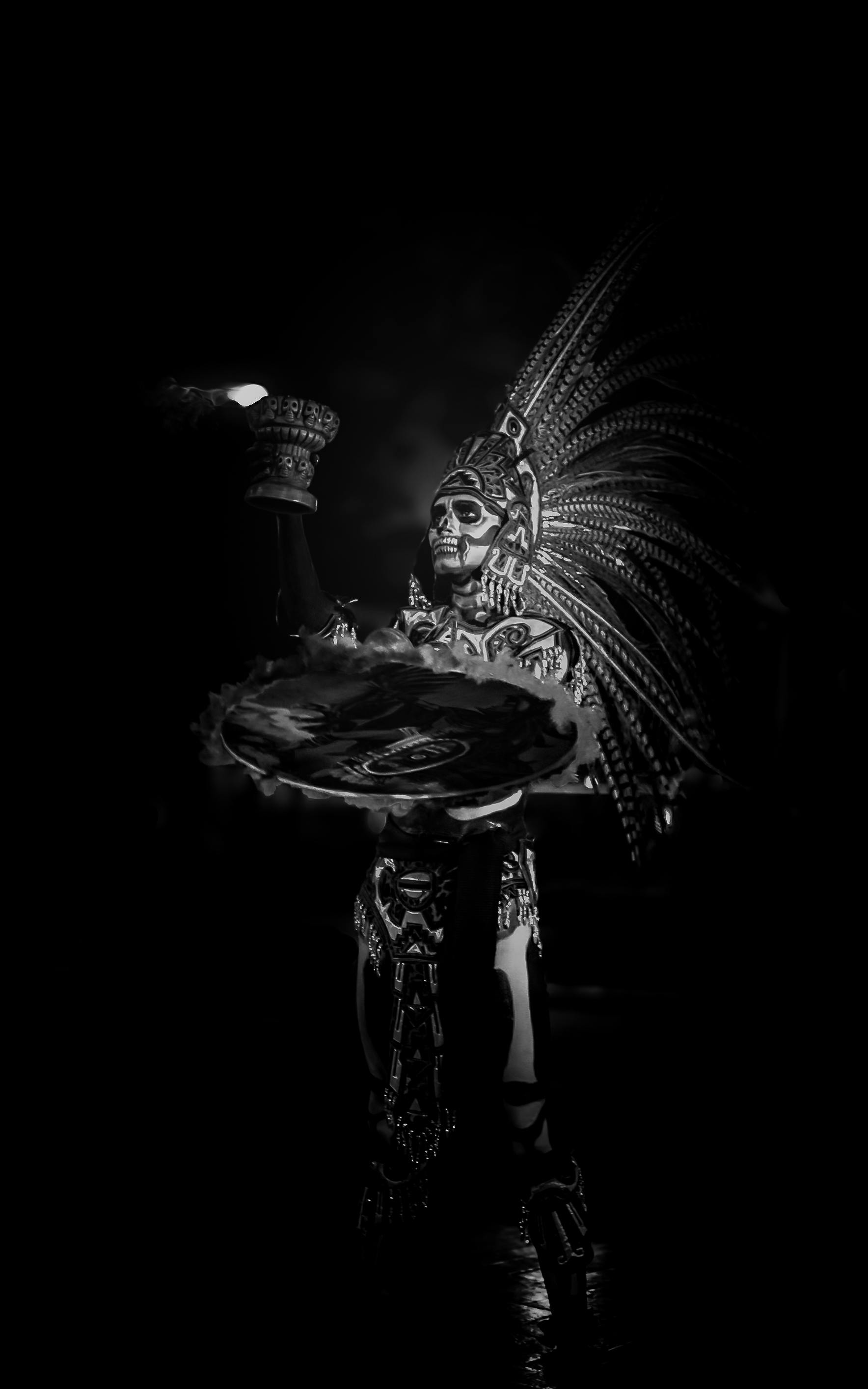 Black and white photo of a Dia de Muertos performer in Mexico City with elaborate makeup and attire.