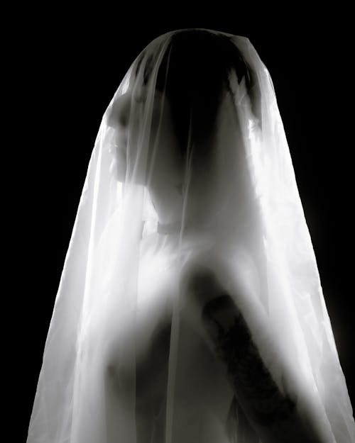 A woman in a veil standing in front of a black background