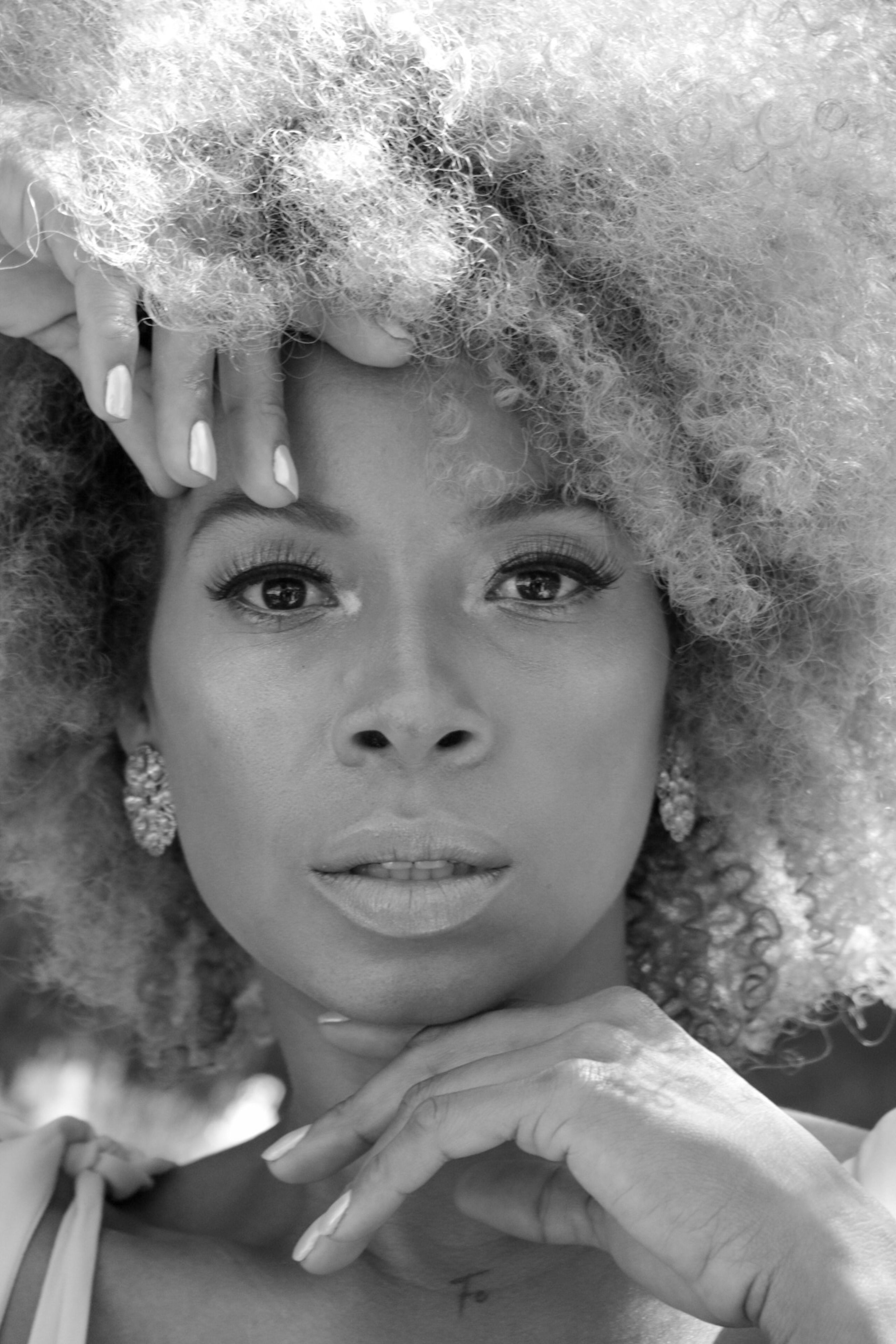 Serene black and white close-up portrait of a young woman with afro hair.