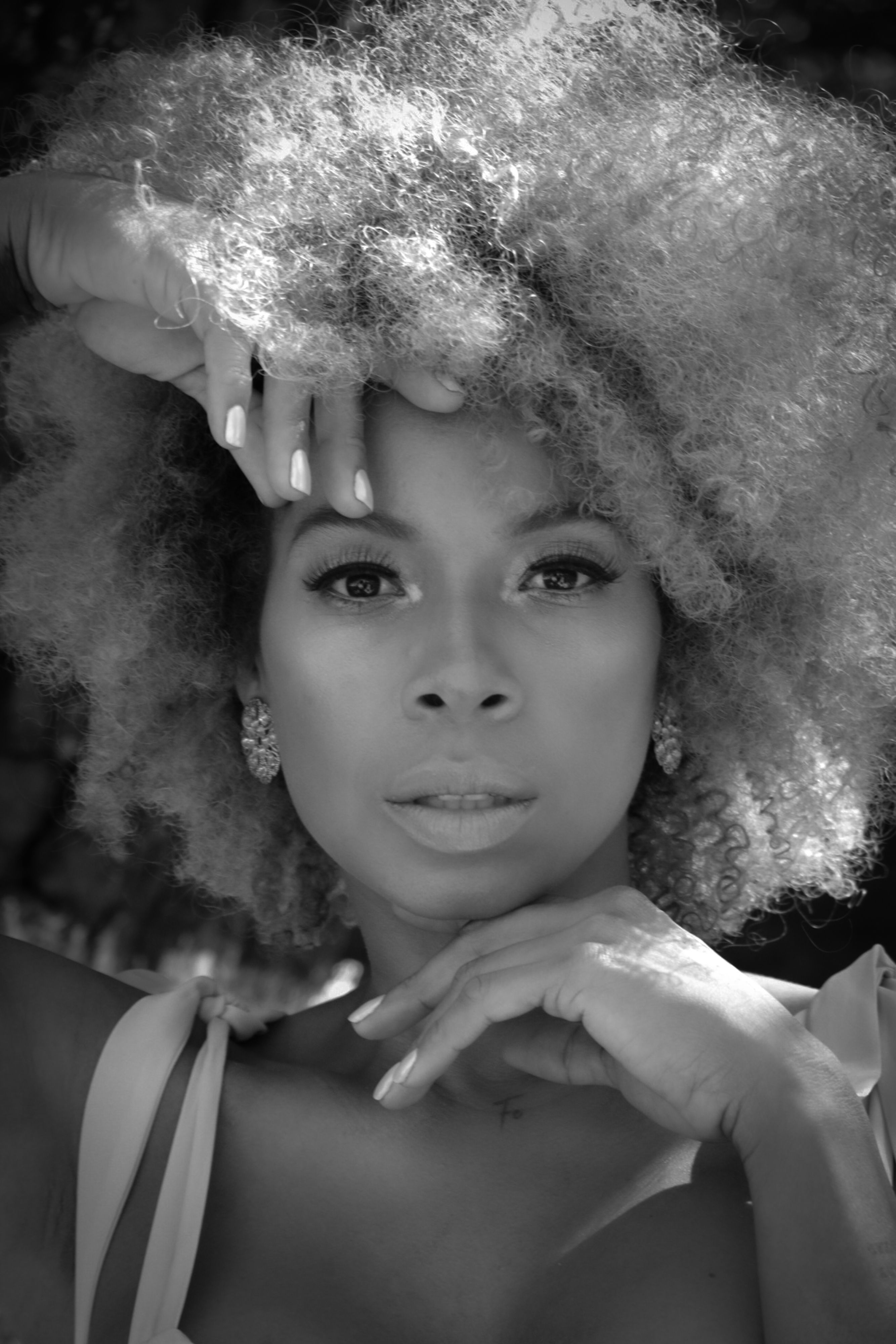 Black and white portrait of a young woman with afro hair, exuding elegance and confidence.