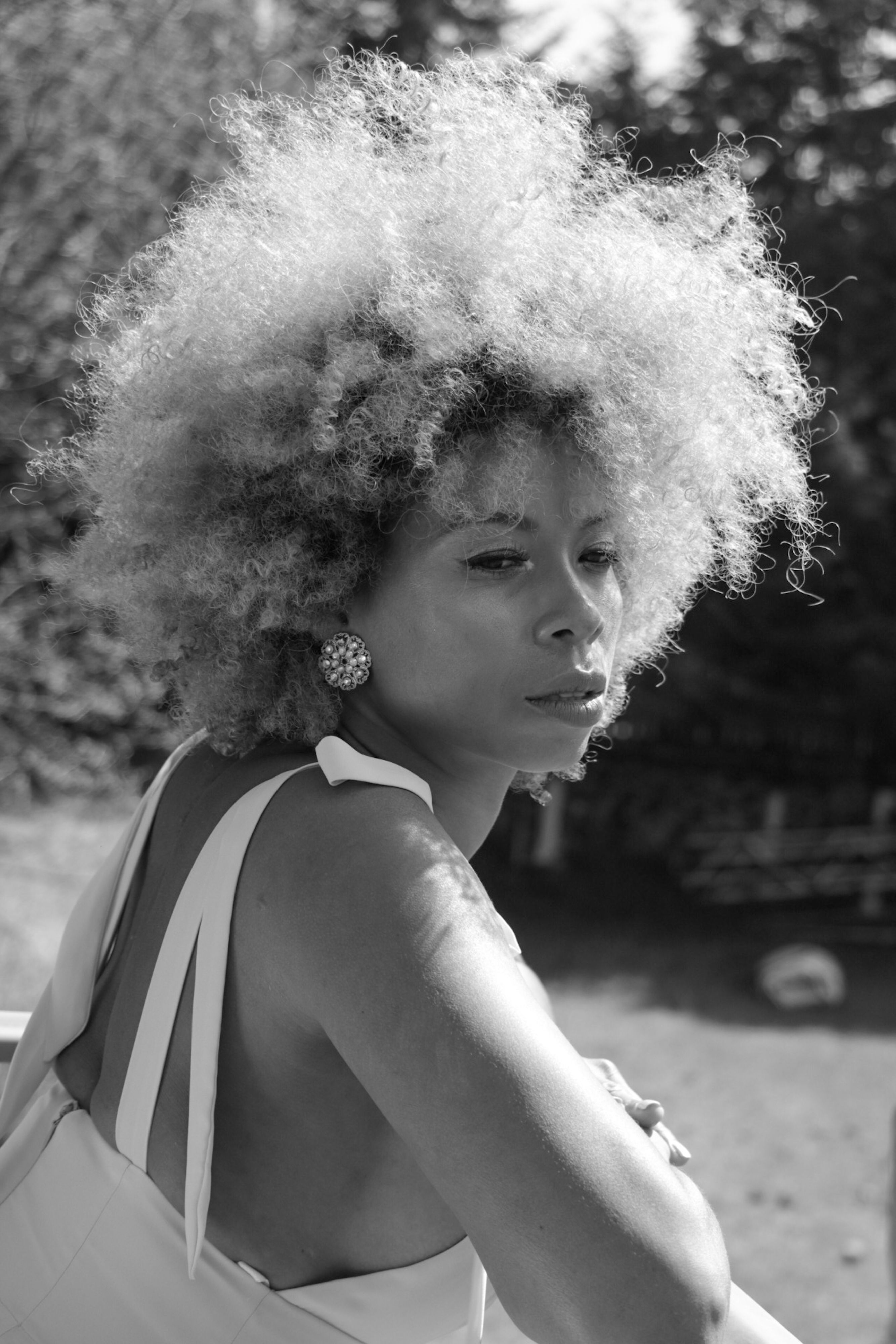 Black and white portrait of a serene woman outdoors with sunlight highlighting her features.