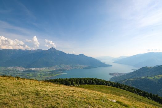 Breathtaking view of Lago di Mezzola with mountains and blue skies in Lombardy, Italy.