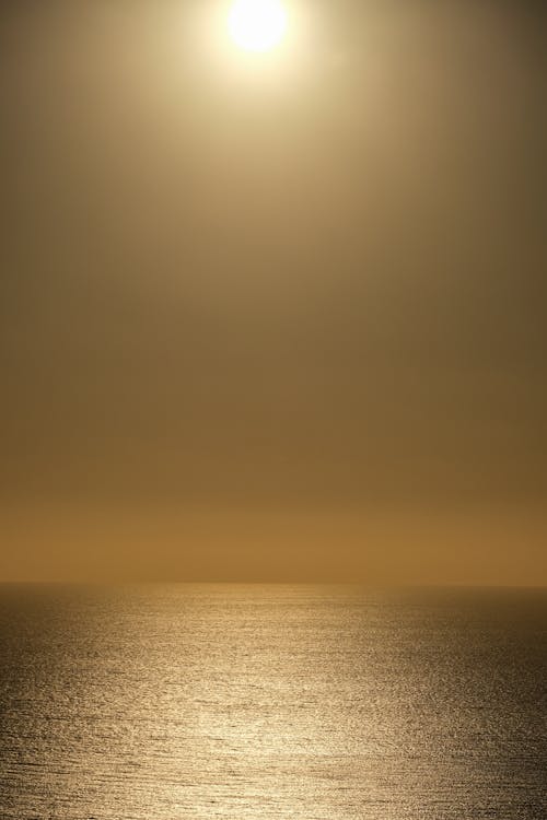 A sun setting over the ocean with a boat in the distance