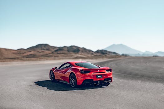 Vibrant red sports car racing along a winding road in a vast desert landscape.