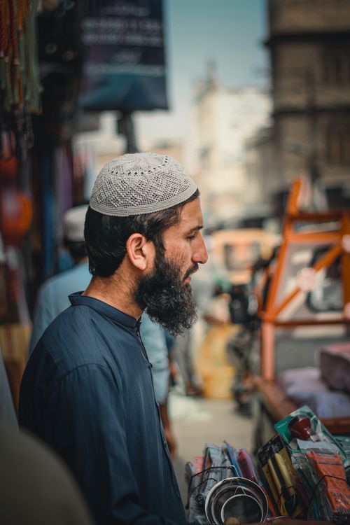 Free Side profile of a man in an urban street market, standing outdoors, vibrant urban environment. Stock Photo