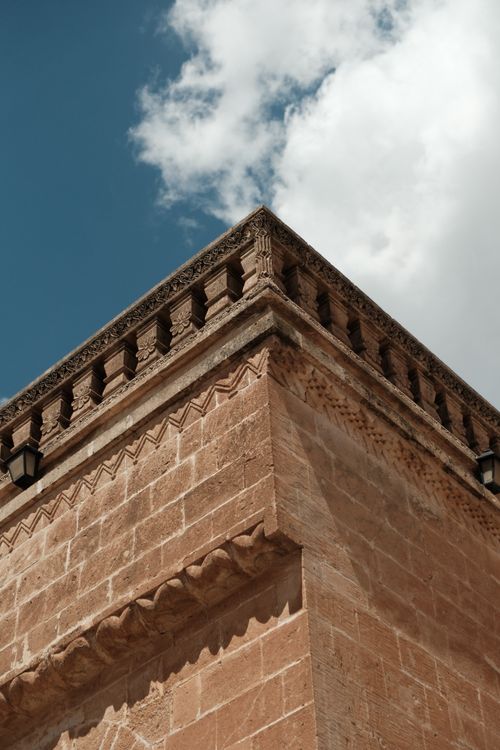 Free Corner view of a historic sandstone building in Midyat, showcasing intricate designs under a blue sky. Stock Photo