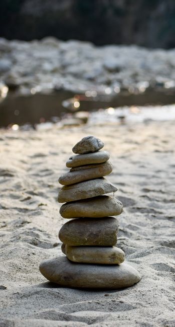 Fotomural Una pila serena de piedras en la playa de arena, ejemplificando equilibrio y armonía.
