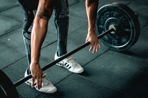 Free Focused athlete preparing to lift a heavy barbell. Indoor gym setting. Stock Photo