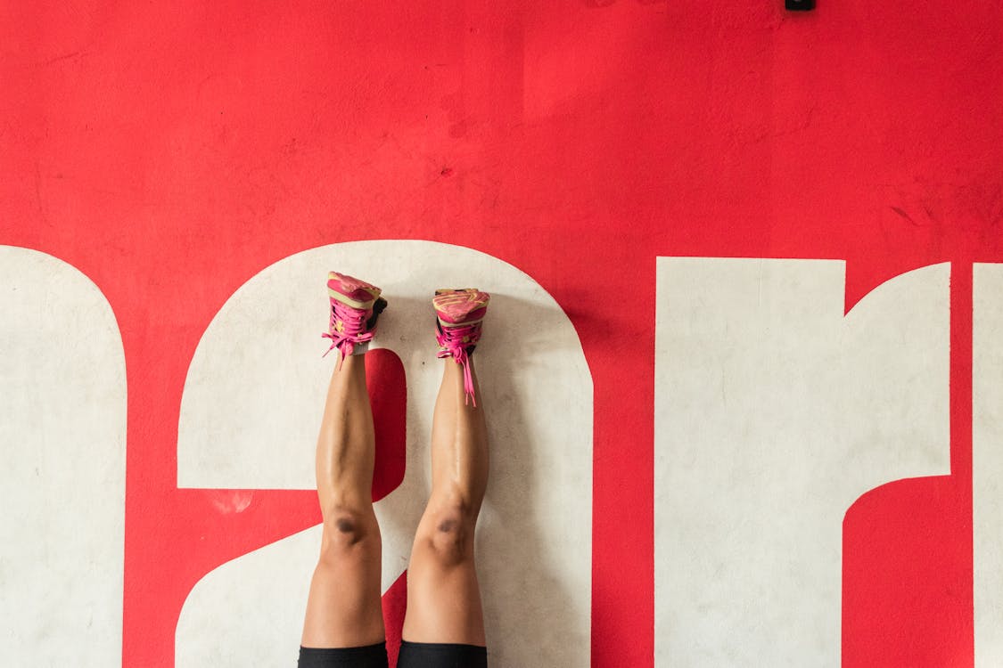 Person in Black Shorts and Pink Sneakers Lying on Floor