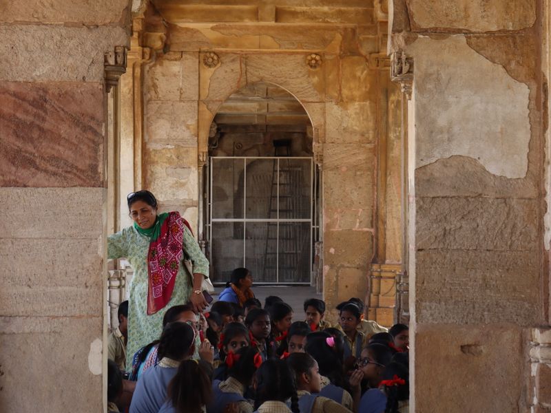 Group of children learning while sitting inside an ancient stone archway - school district licensing