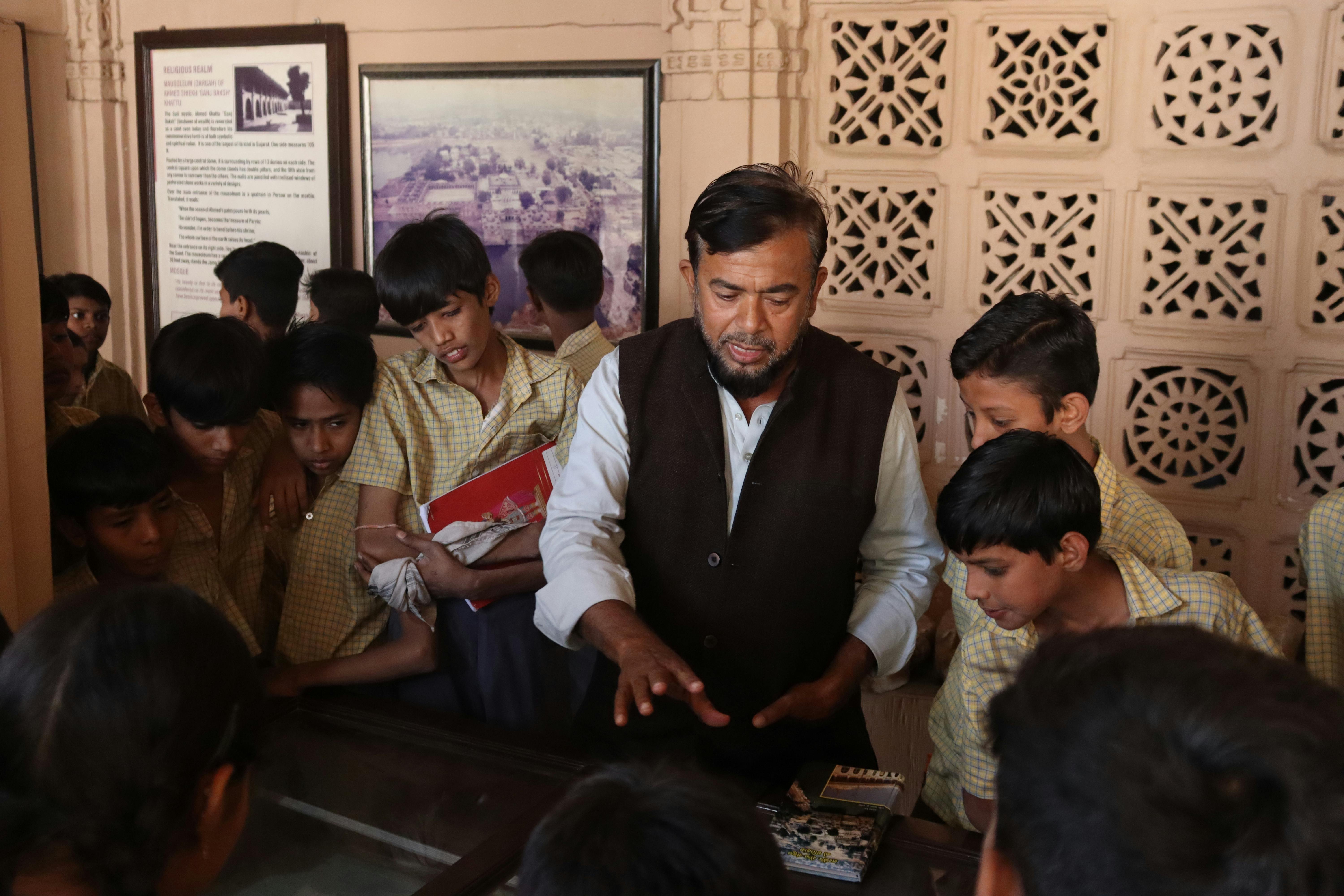 Group of school children on a heritage tour with a guide in an Indian museum.