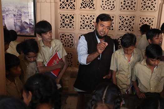Teacher guiding attentive students during an interactive indoor lesson, fostering education.