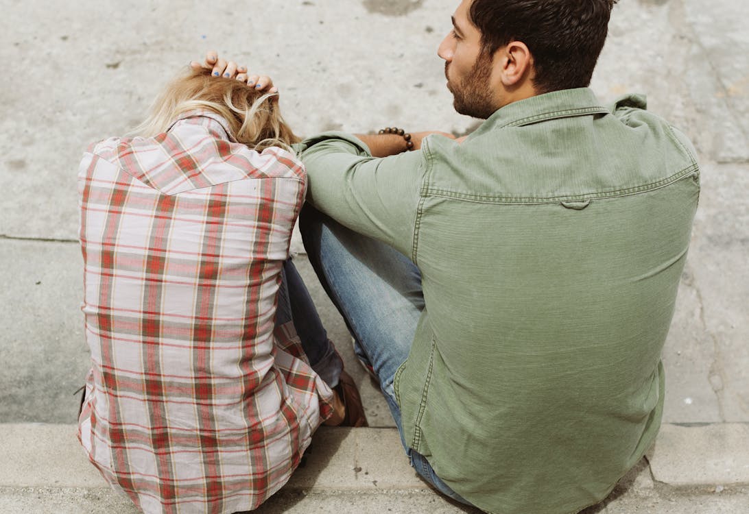 Free Man and Woman Sitting on Sidewalk Stock Photo