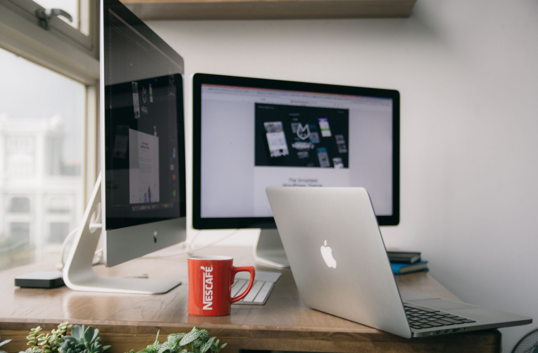 website performance optimization - A bright modern office setup with computers and a mug on a desk.