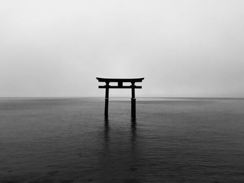Free Black and white photo of a Torii gate reflecting on calm waters, capturing a serene, minimalist aesthetic. Stock Photo