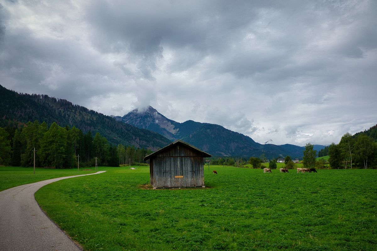 Cabana de lemn pe o pasune alpina cu creste in fundal