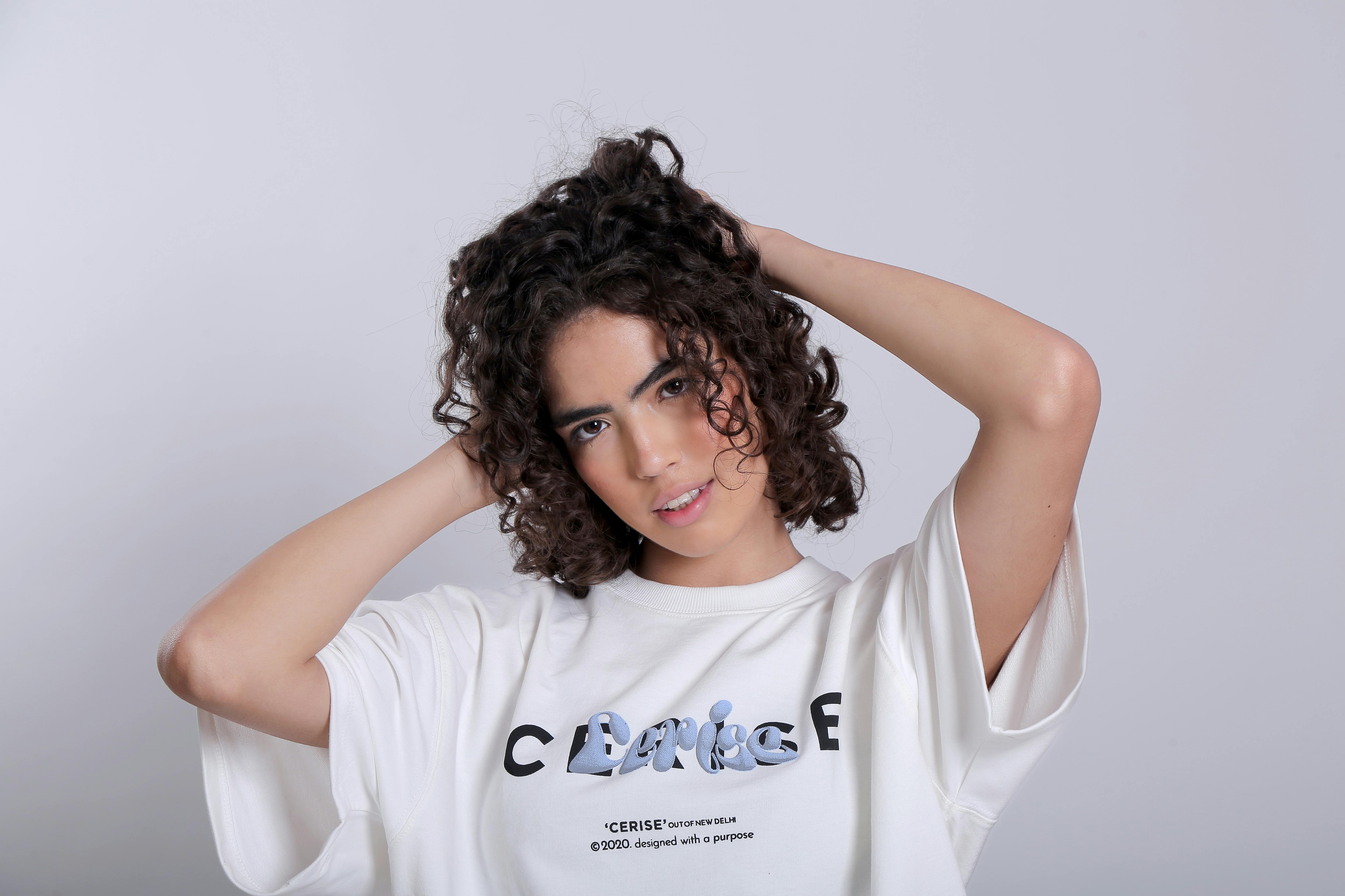 Stylish woman with curly hair posing confidently in a studio setting.