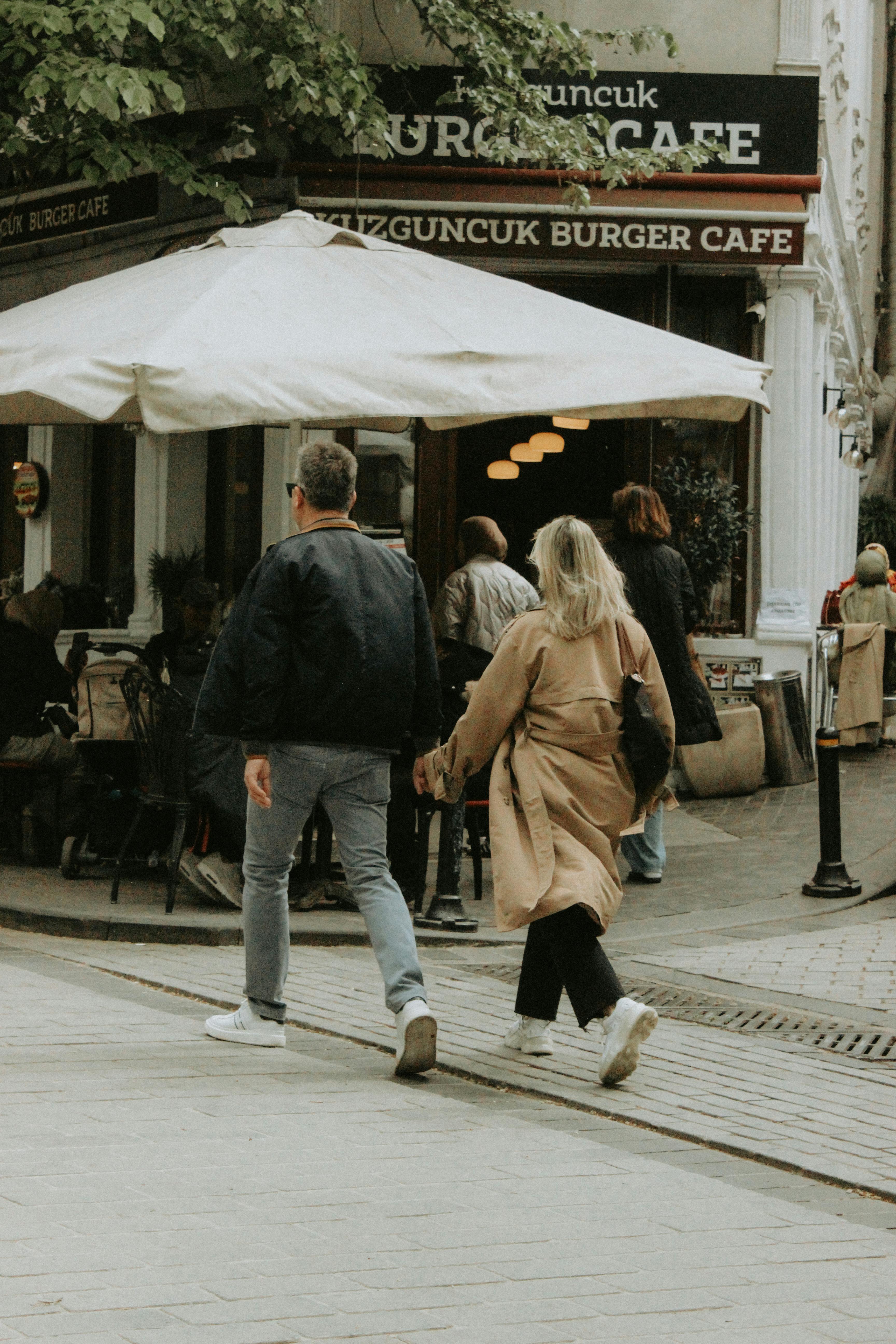 A couple walks by Kuzguncuk Burger Café on a lively street in Turkey.