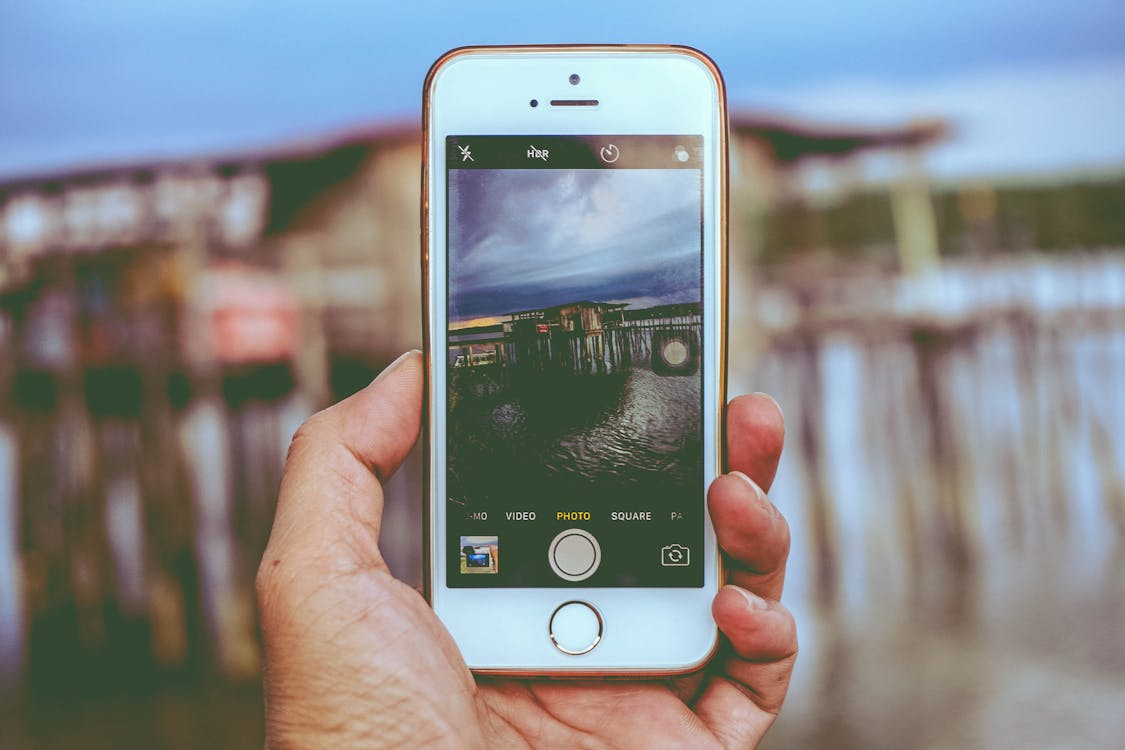 免费 图片持有iphone拍照在海滩上的房子 素材图片