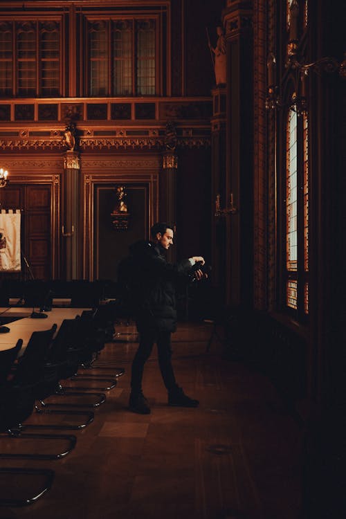 Man in Jacket and with Camera in Vintage Hall