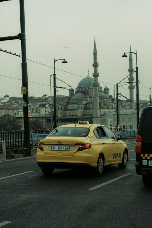A taxi is driving down the road next to a mosque