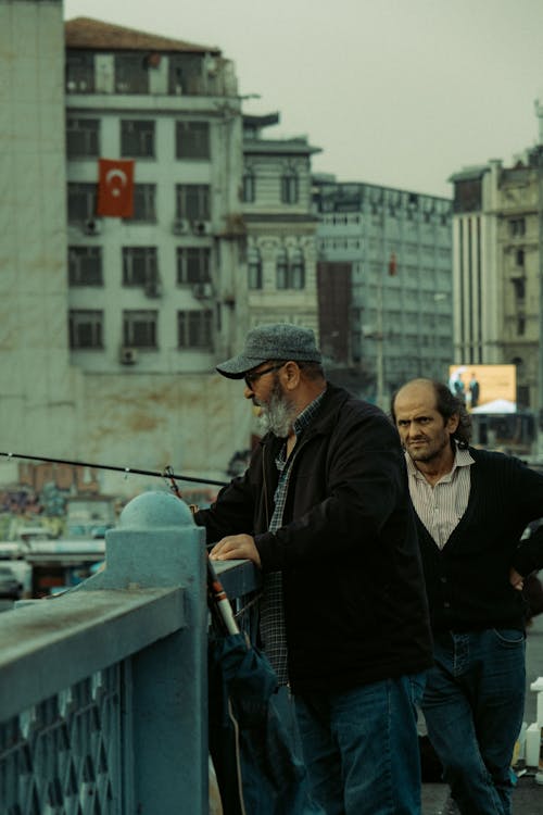 Two men standing on a bridge with a fishing pole