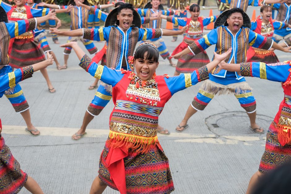 Colorful street festival with dancers in traditional attire joyously performing in unison.