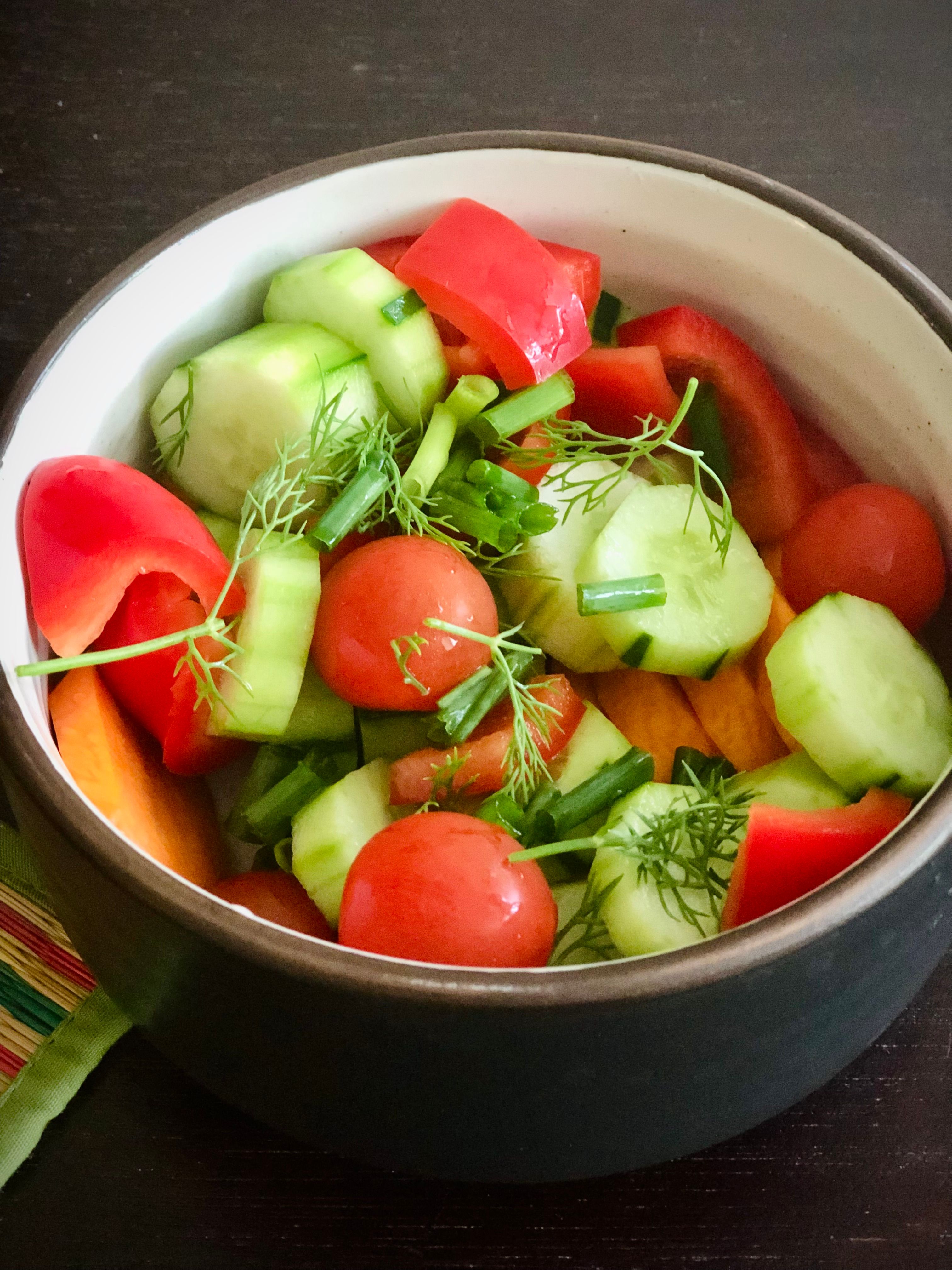 Vibrant bowl of fresh vegetable salad featuring cucumbers, tomatoes, and bell peppers.