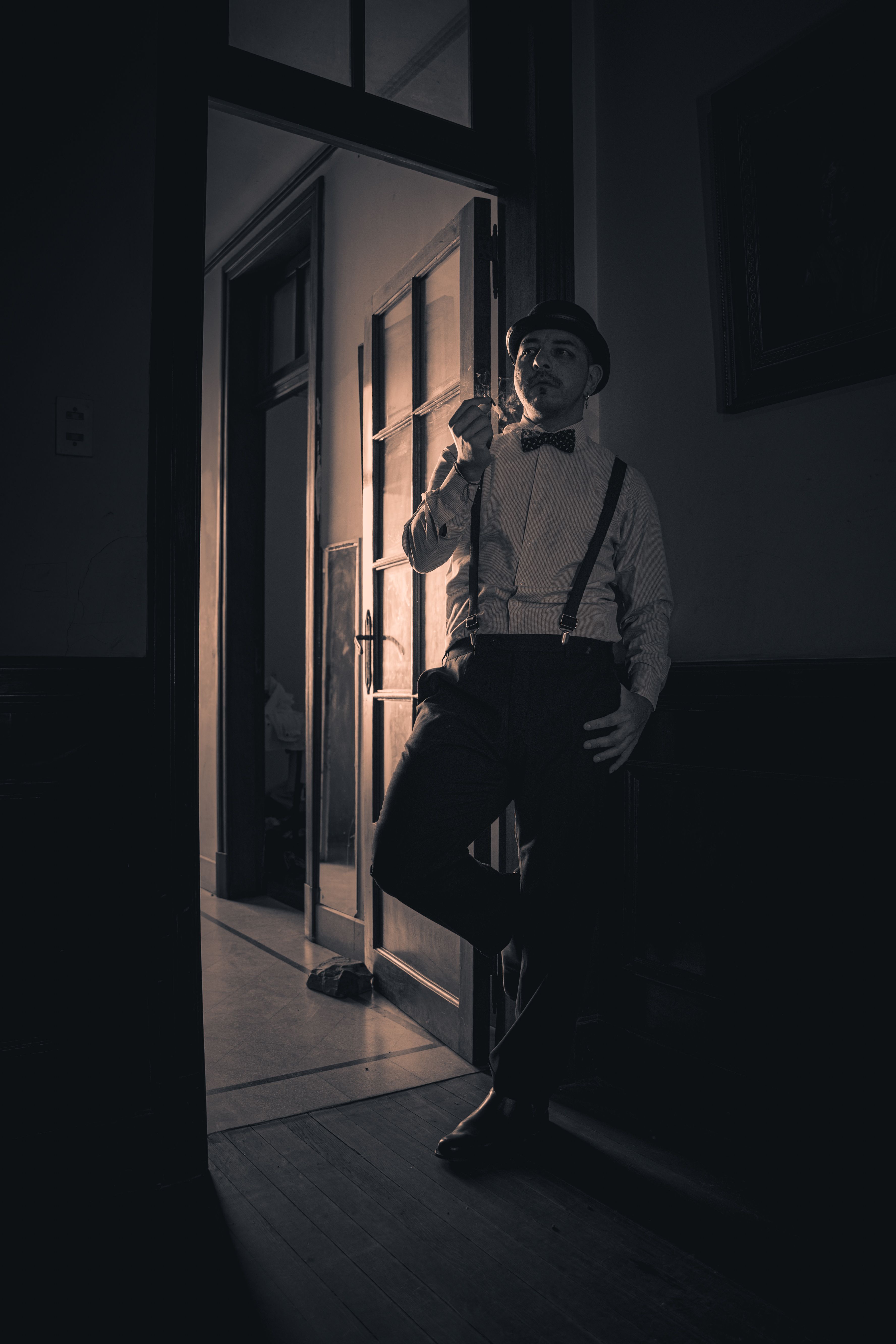 Elegant black and white portrait of a man in retro attire, wearing a bow tie and suspenders.