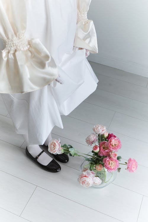 Flowers under Legs of Woman Standing in White Dress