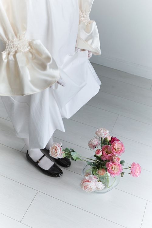 Free High angle view of a woman in a white dress with flowers on a bright floor, conveying elegance and simplicity. Stock Photo