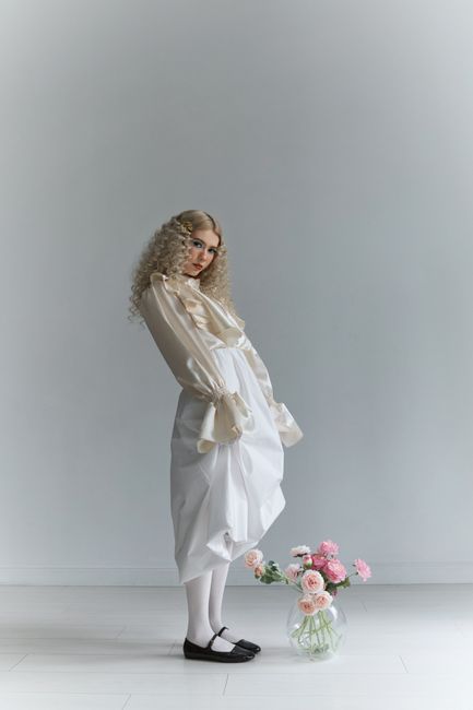 Sophisticated fashion model in white attire with flowers, offering a modern elegant look.