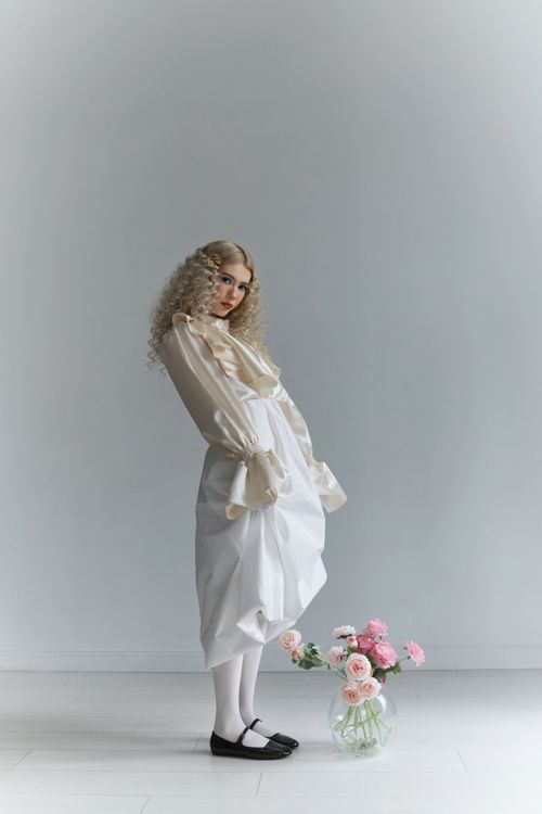Free Sophisticated fashion model in white attire with flowers, offering a modern elegant look. Stock Photo