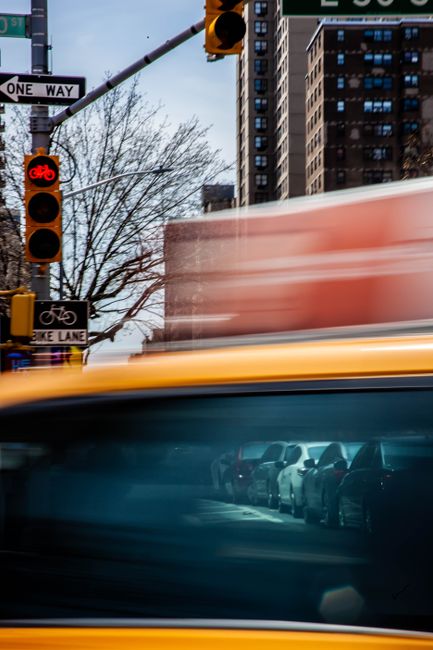 Motion-blurred vehicles and urban streetlights in a bustling city environment captured at dusk.