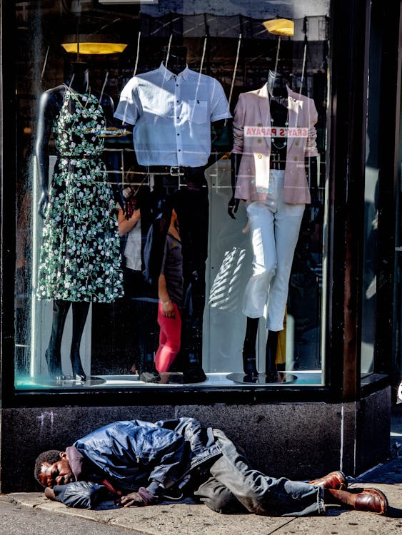 Photo of Homeless Man Sleeping In Front of Clothing Store