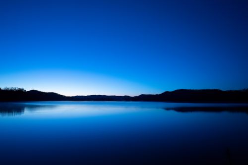 Free Capture of a tranquil lake at twilight in Tell, WI, with deep blue skies reflecting on calm water. Stock Photo