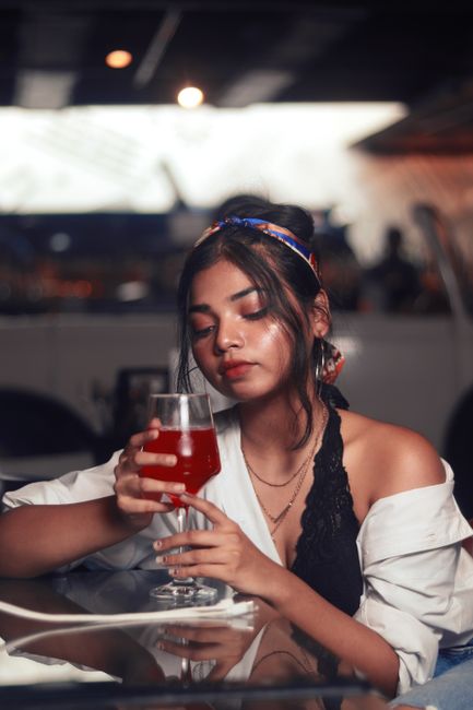 Stylish young woman with a cocktail at a chic indoor setting, exuding elegance and charm.