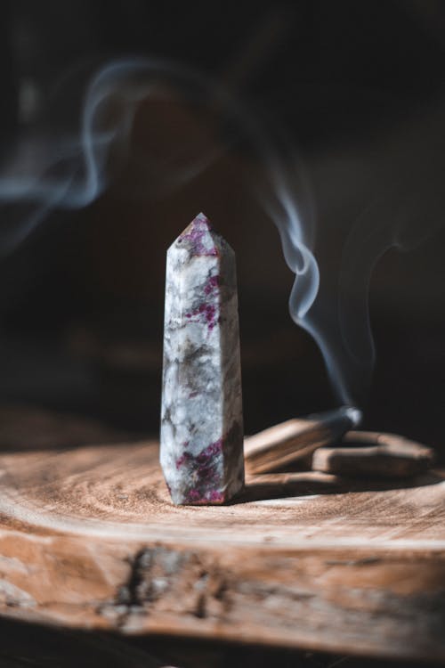 A purple crystal on top of a wooden stick