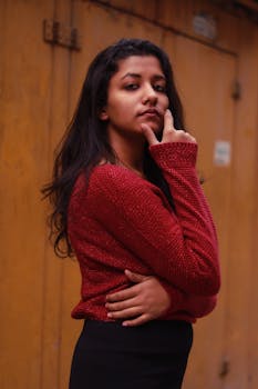 一位时尚女性穿着红色毛衣，在木制背景下自信地摆姿势