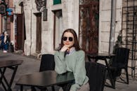 一位时尚女士在城市咖啡馆里，戴着太阳镜享受阳光明媚的日子