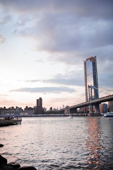 日落时分，风景秀丽的纽约市天际线在东河上横跨着曼哈顿大桥