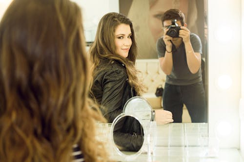 Мужчина фотографирует девушку в зеркале