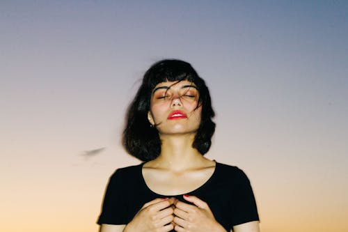 A woman in black shirt with hands on her chest