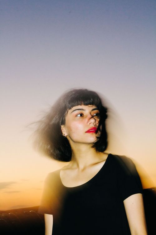 Free Portrait of a young woman with short hair posing outdoors during sunset. Stock Photo
