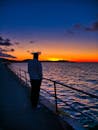 一个人独自站在海滨长廊上，凝视着海上充满活力的日落