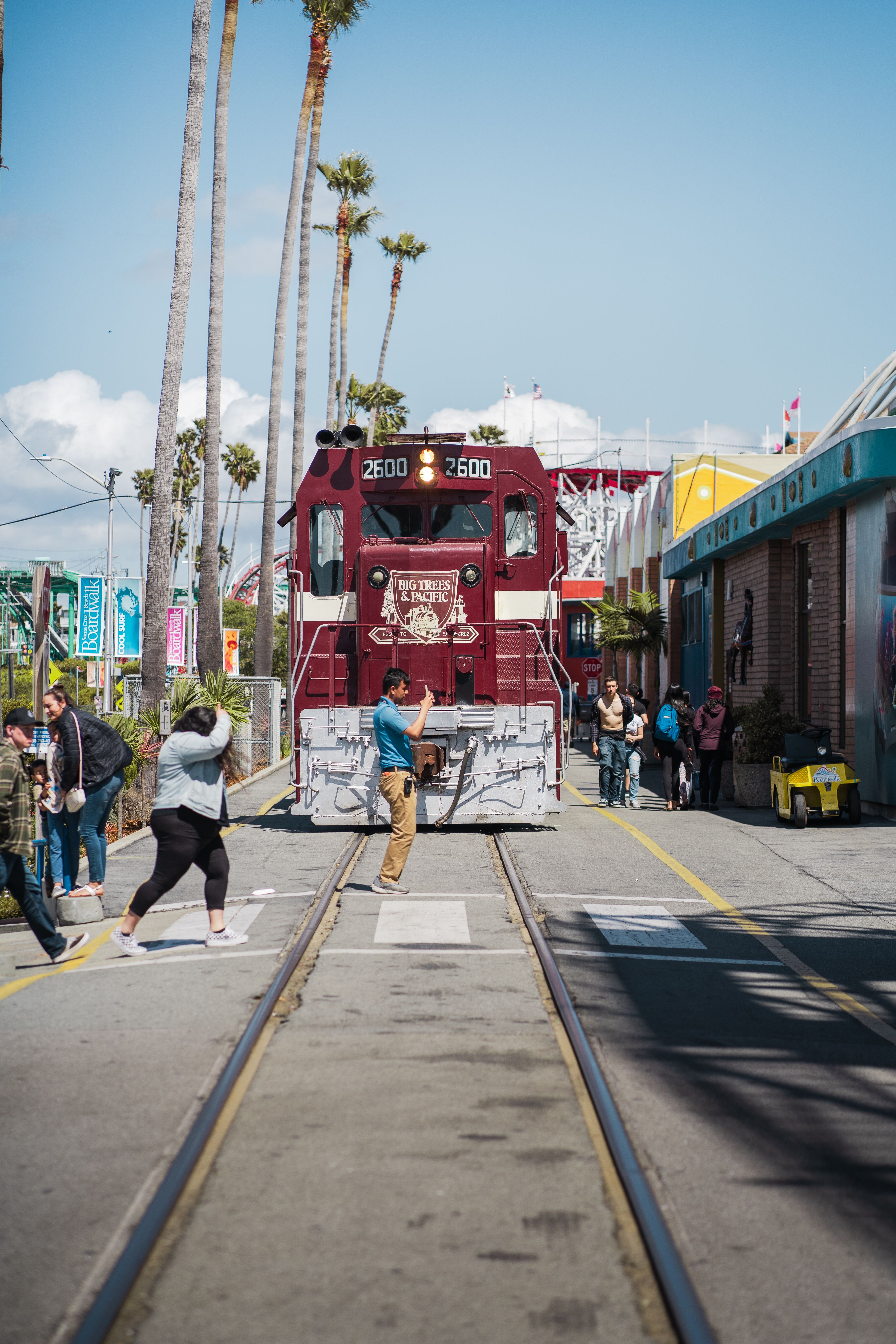 A historic maroon train runs on tracks near Santa Cruz Beach Boardwalk, California.