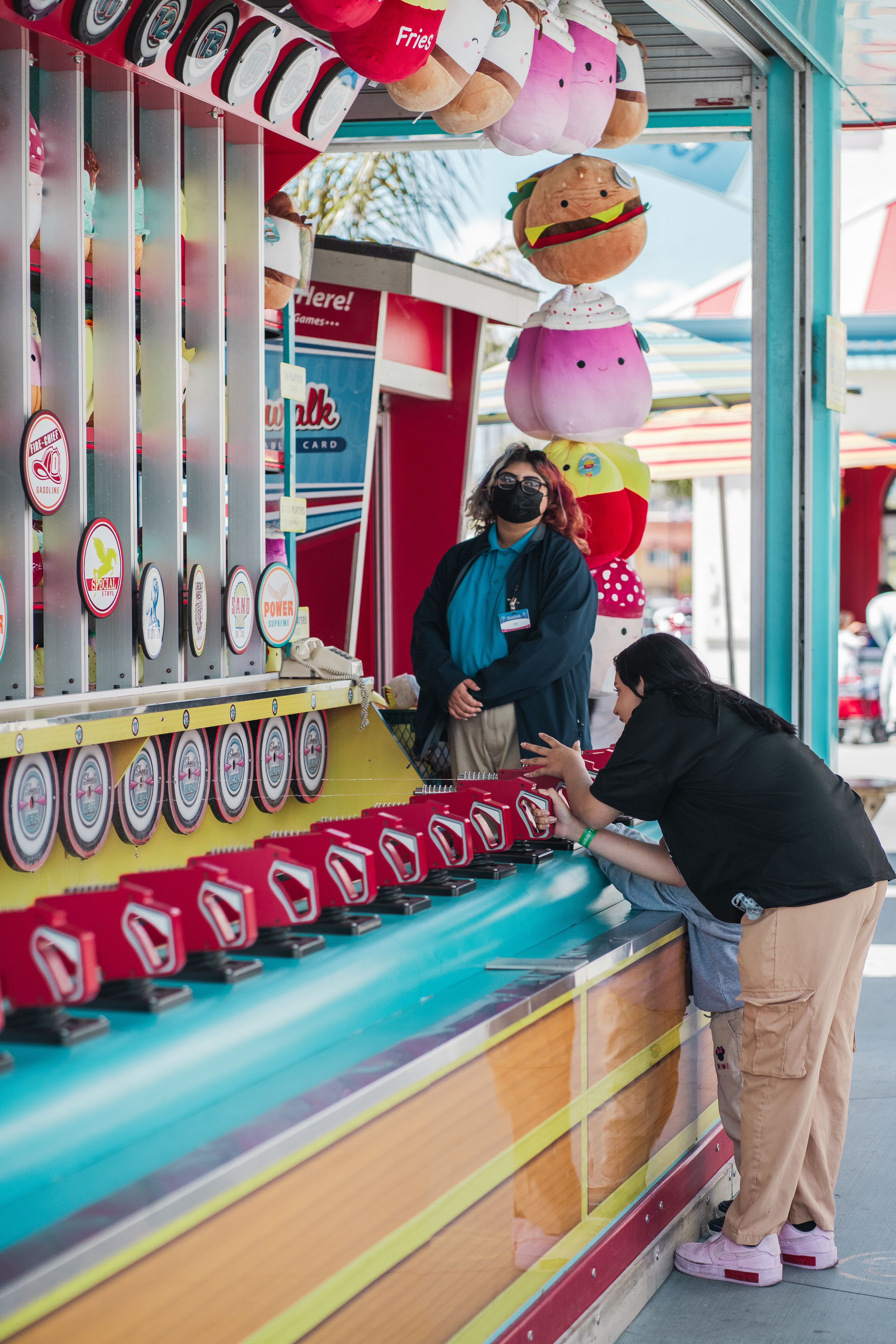 A fun game stand at an amusement park in Santa Cruz, California, with people participating.