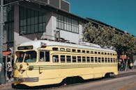 阳光明媚的日子里，一辆经典的黄色老式有轨电车穿行在城市景观中