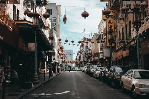 Free Busy daytime street view in San Francisco's Chinatown with shops, cars, and hanging lanterns. Stock Photo