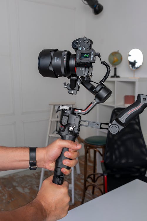 A person holding a camera and holding a tripod